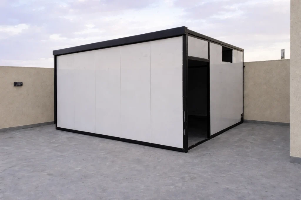 غرفة جاهزة مكتملة فوق سطح مبنى سكني بتصميم حديث بجدران بيضاء وإطار أسود أنيق