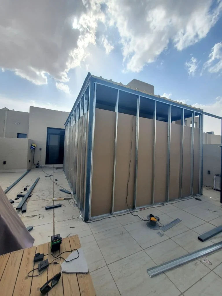 هيكل معدني لجدران غرفة جاهزة قيد التنفيذ فوق سطح منزل مع تجهيزات التركيب
